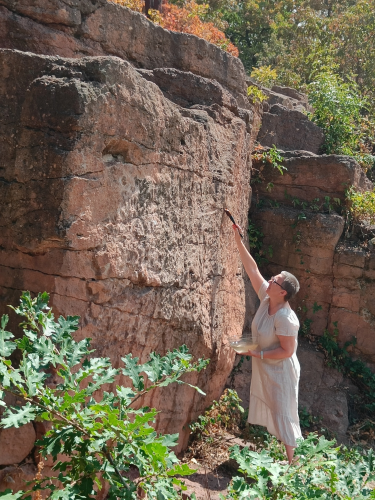 Artist painting with water on rock surface in a quarry
